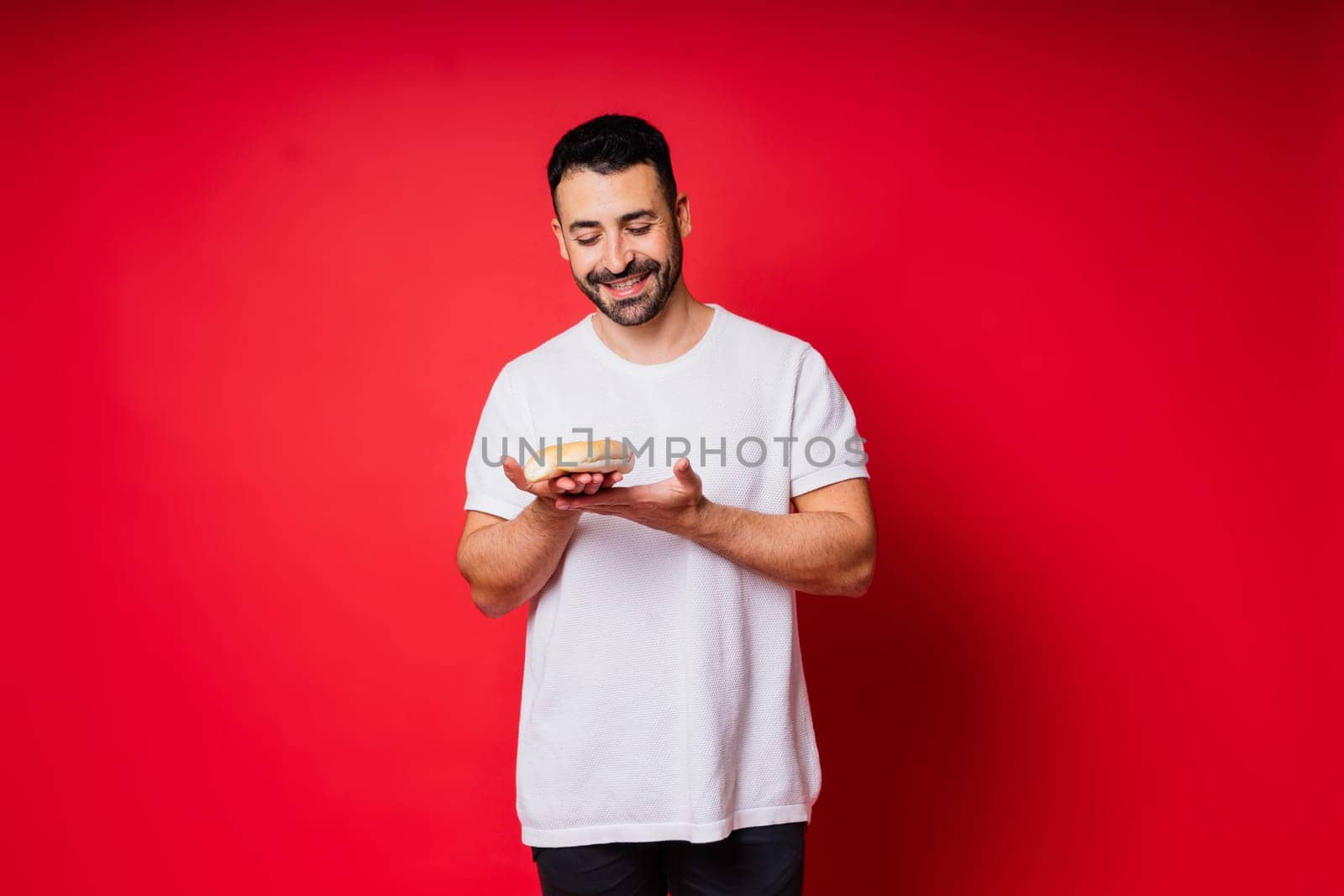 Man holding freshly baked bread in hands isolated on red background by Zelenin