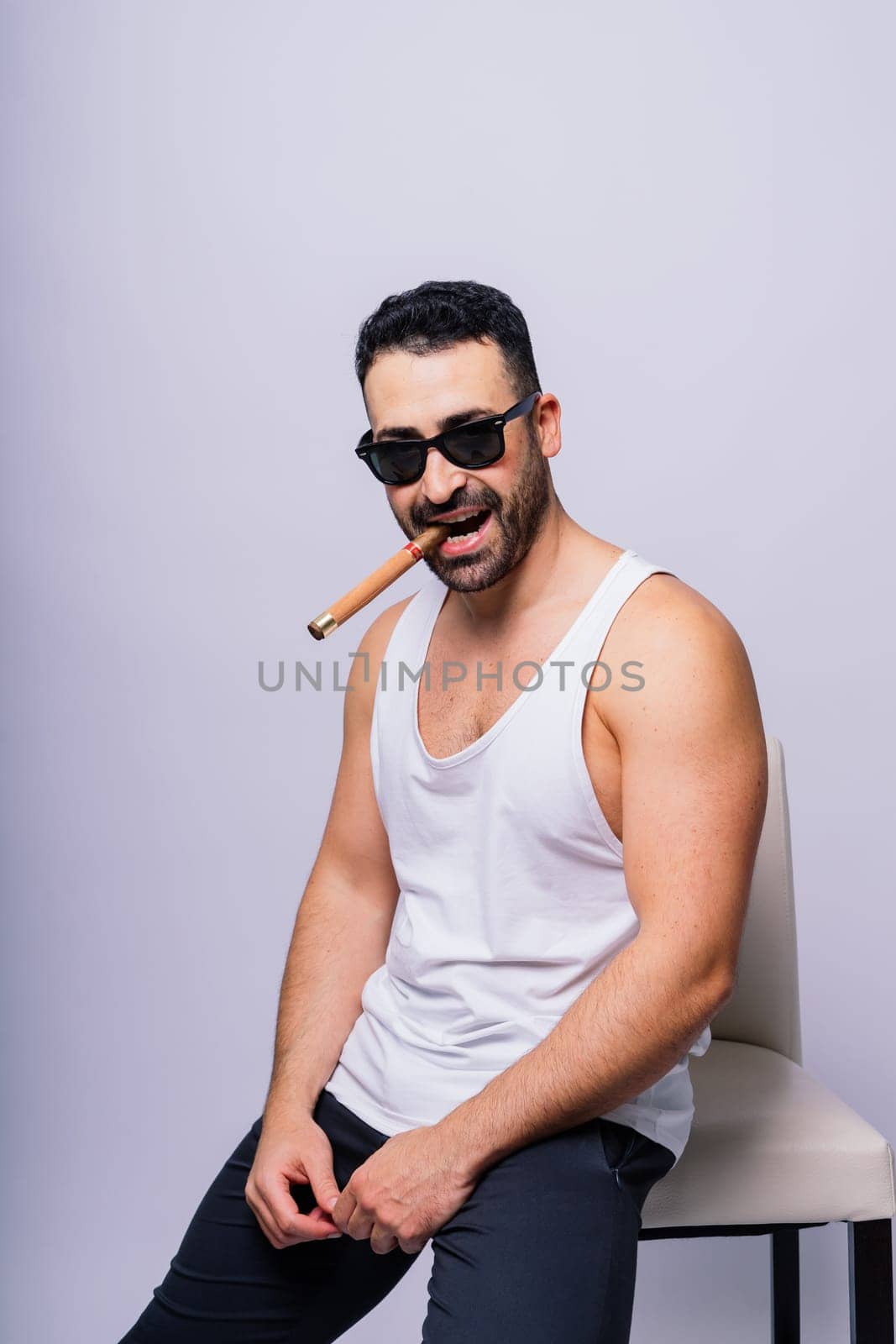 Young man with beard smoking a cigar in studio by Zelenin