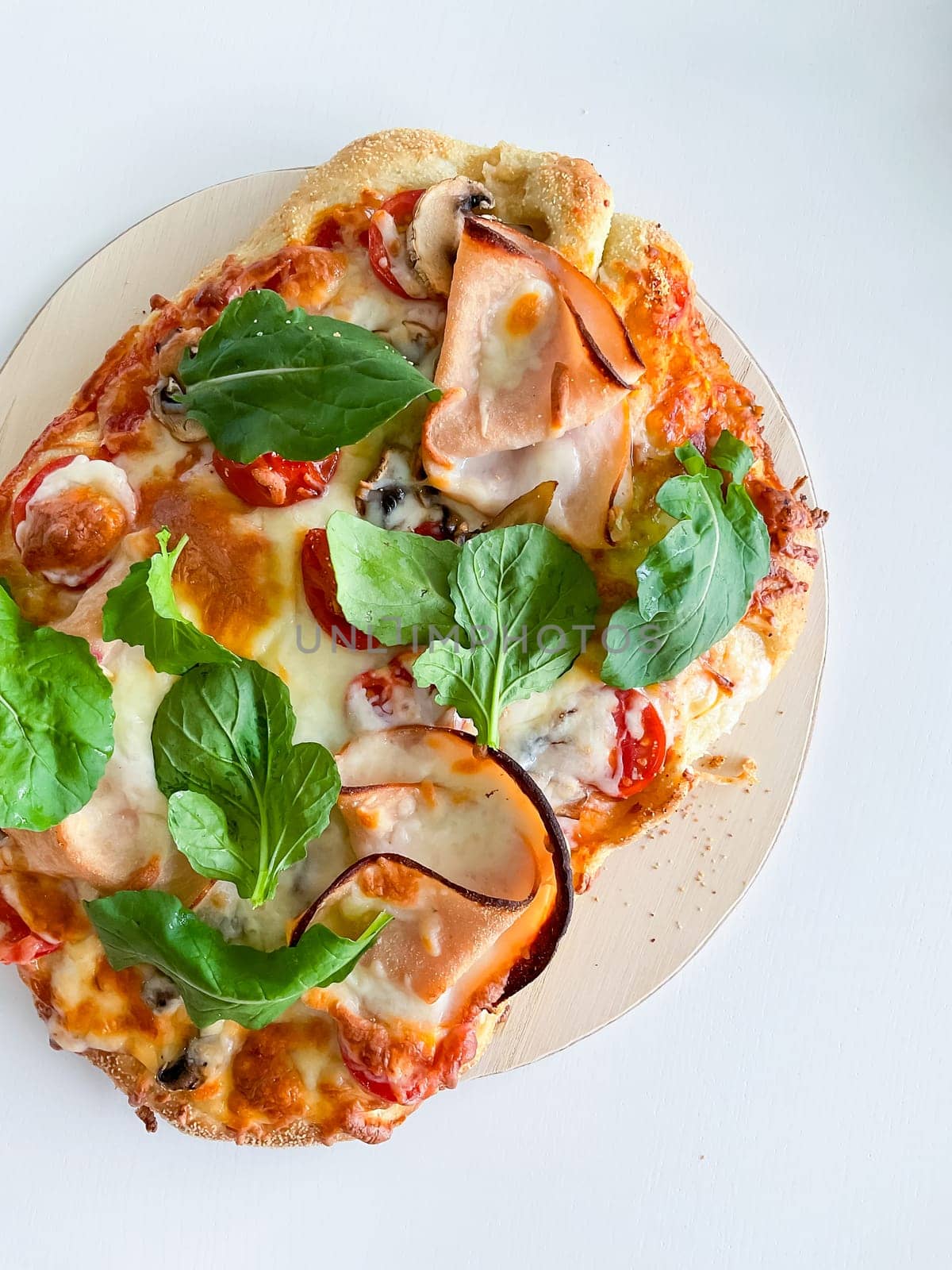 Pizza with ham, mozzarella, tomatoes and leaves on a white background. View from above by Lunnica