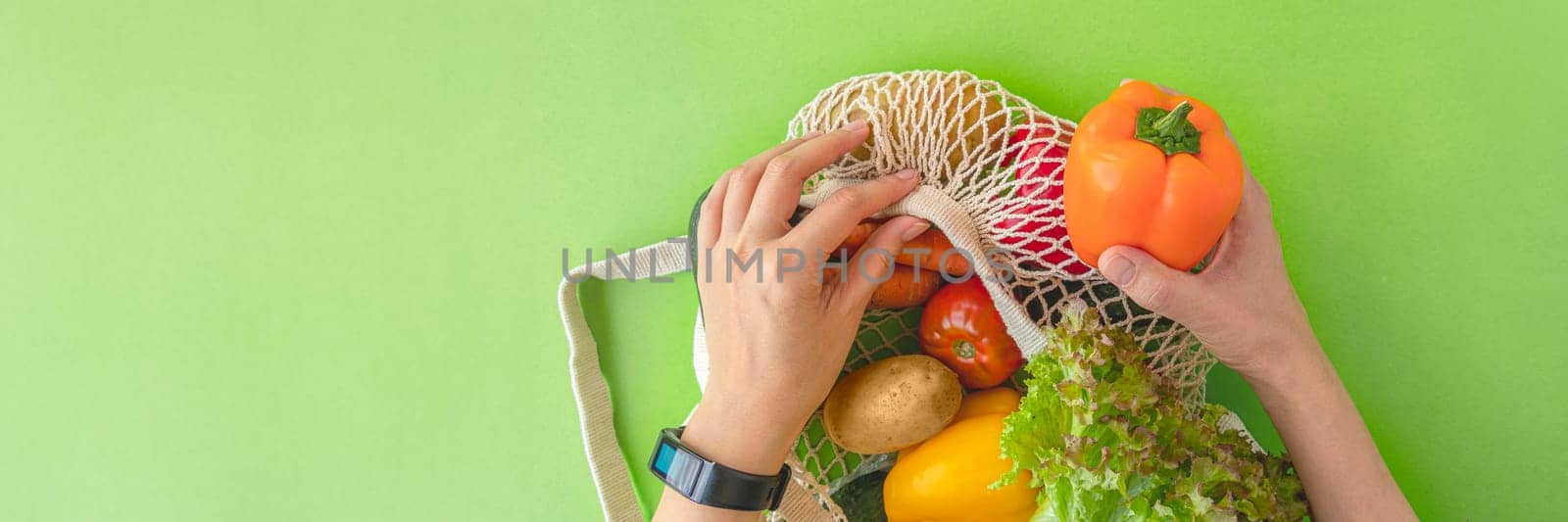 banner of top view of a woman's hands taking vegetables out of an eco-bag. tomatoes, cucumbers, bell peppers and lettuce in a reusable bag. The concept of recycling, respect for nature. flat lay, copy space.