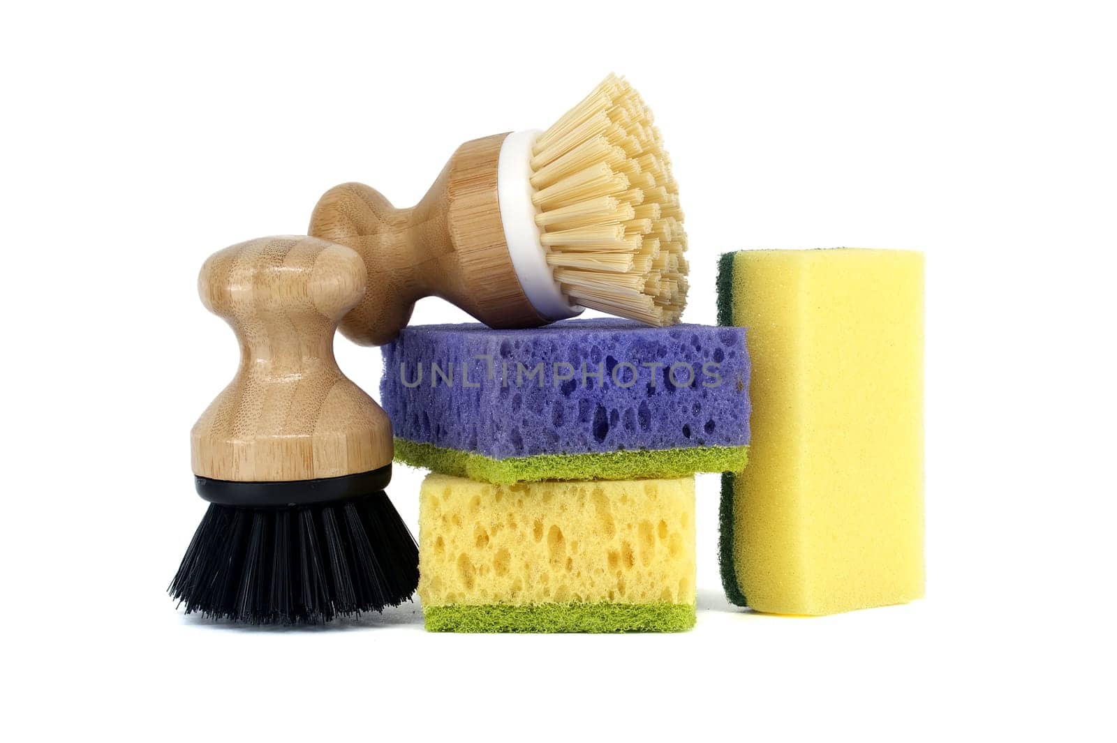 Three sponges, each a different color purple, yellow, and blue and two brushes with wooden handles isolated on white background, cleaning tools