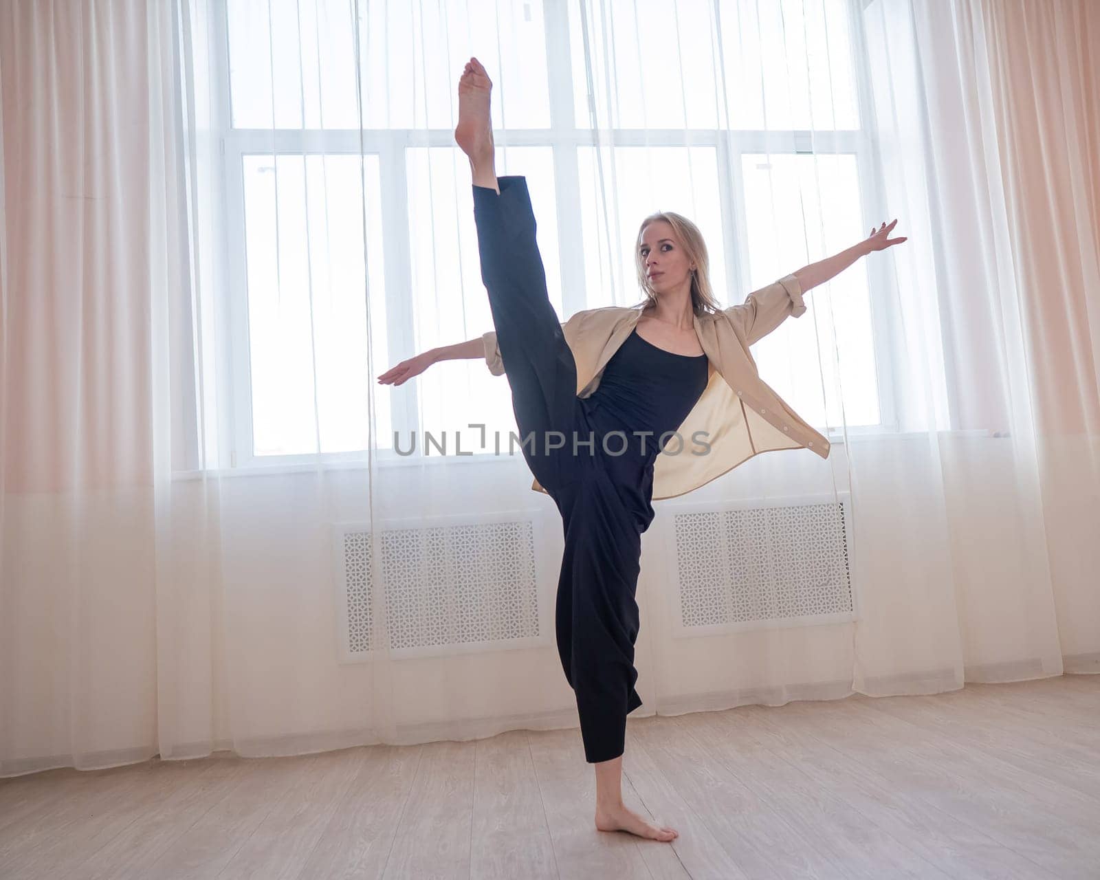 Caucasian woman dances contemporary in ballet class. Dancer in a jump. Vertical photo. by mrwed54