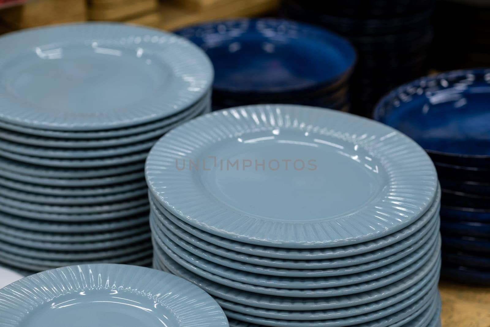 A stack of white mugs and plates in the store for sale. White and clean dishes by AnatoliiFoto
