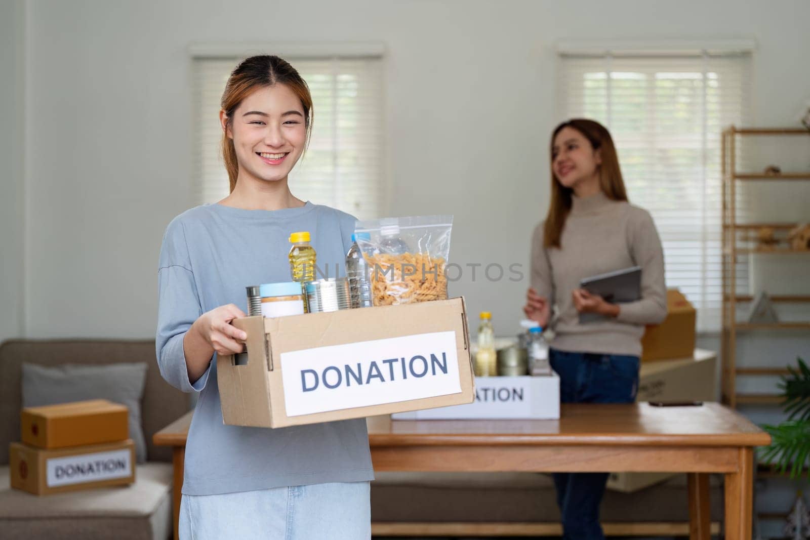 charity, donation and volunteering concept. Volunteer prepare foodstuff box containing food to donate to people poor, disaster victim at home by itchaznong