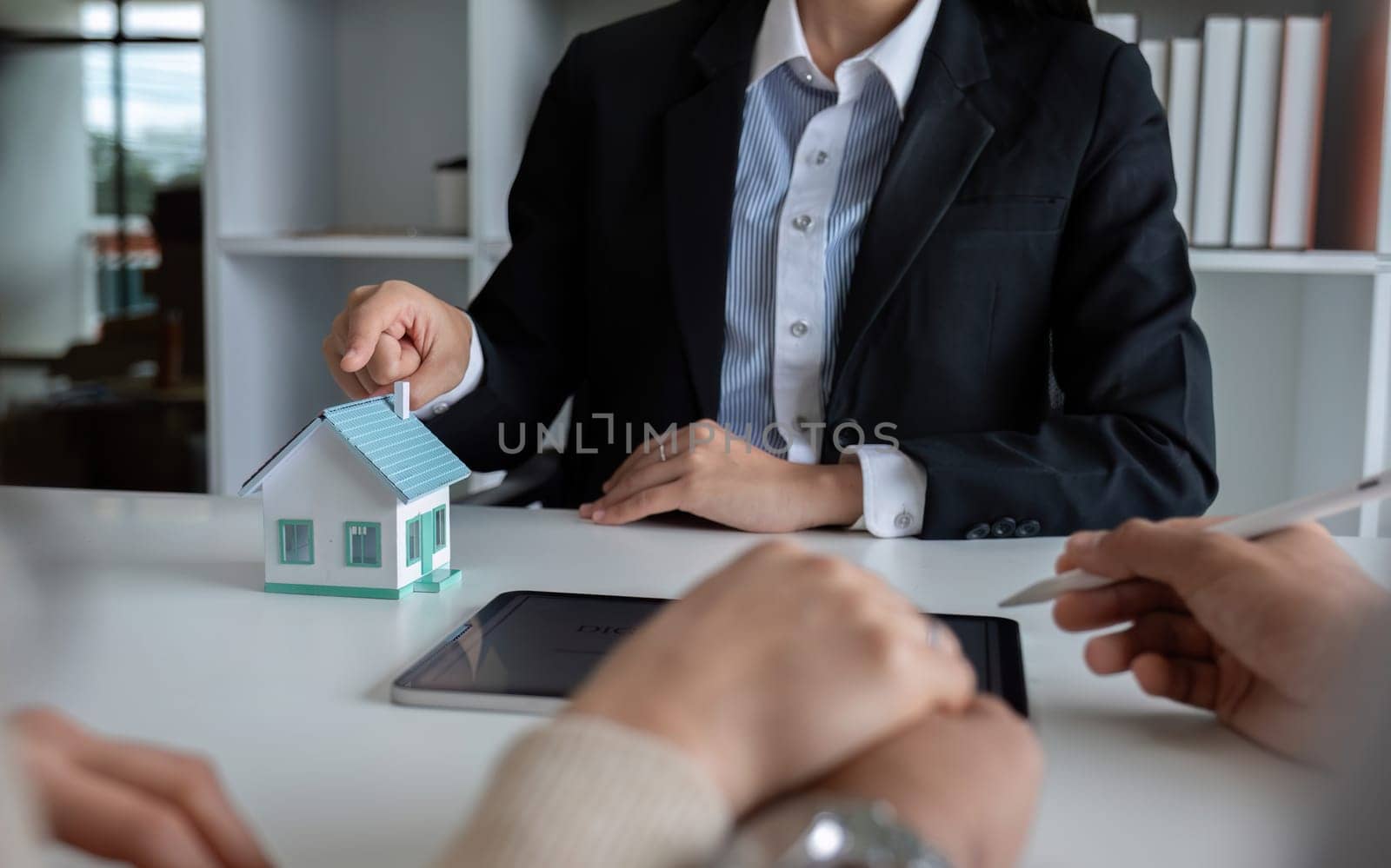 A real estate agent or insurance agent presents a house plan and insurance contract to an Asian couple..