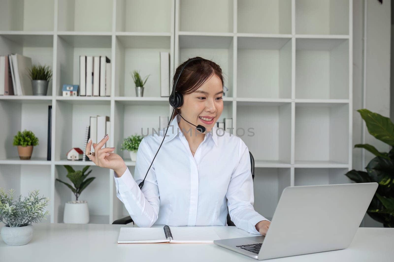 Call center agents wear headphones to talk to customers. Provide consultation via online channels on laptops by wichayada