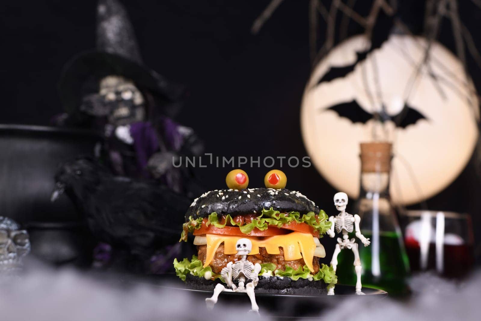 Monster Burger. Black bun, juicy beef cutlet, lettuce, onion, tomato and cheese in the shape of teeth, in the company of skeletons. Definitely a pick-me-up and a perfect Halloween party appetizer