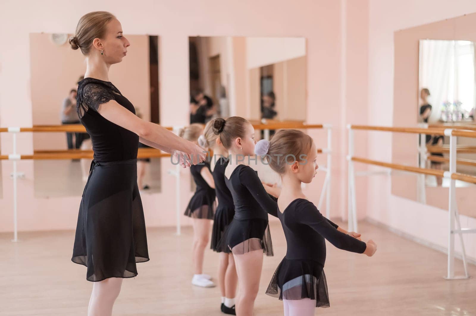 Children's ballet school. Caucasian woman teaching ballet to little girls