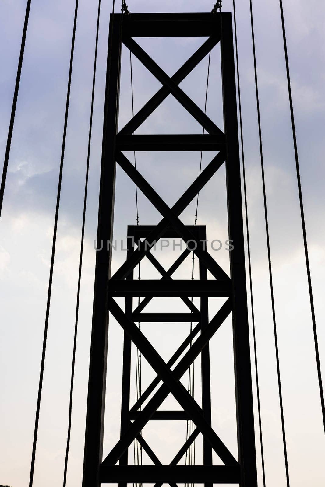 The Iron Black Bridge Under Cloudy Sky. Little Road through metal bridge tunnel over river.