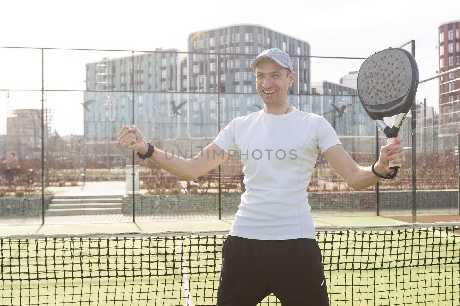 European man holding padel racquet in hand and ready to return ball while playing in court. High quality photo