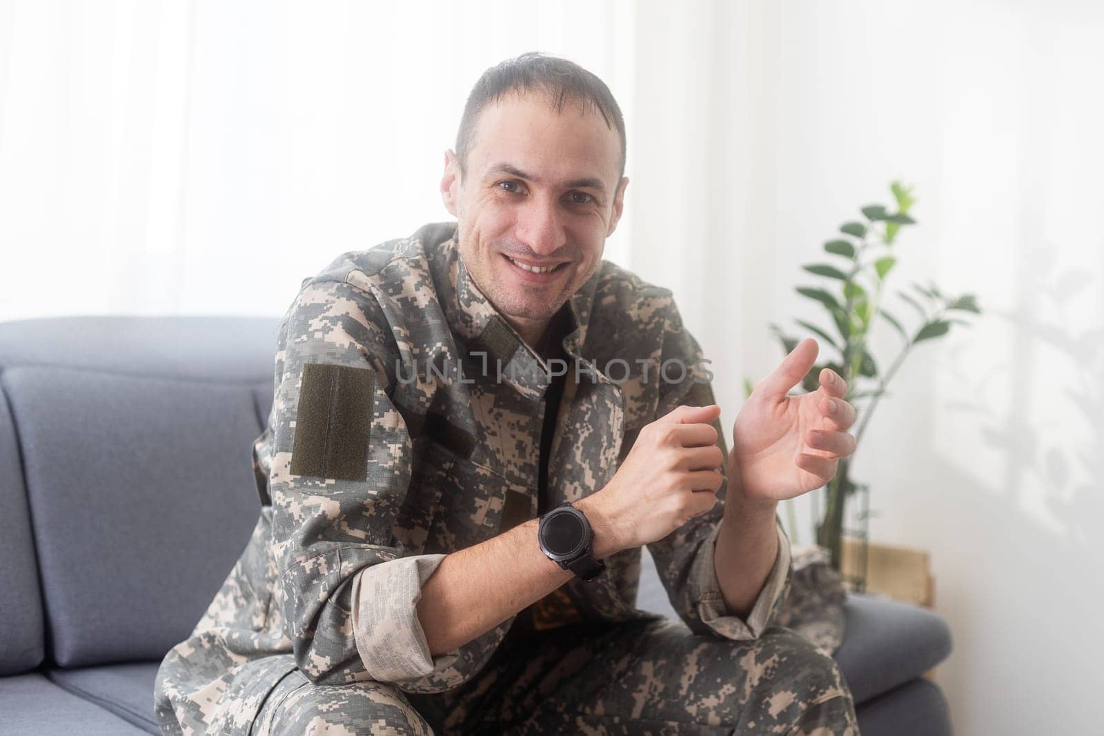 excited army soldier sitting on couch at home. High quality photo
