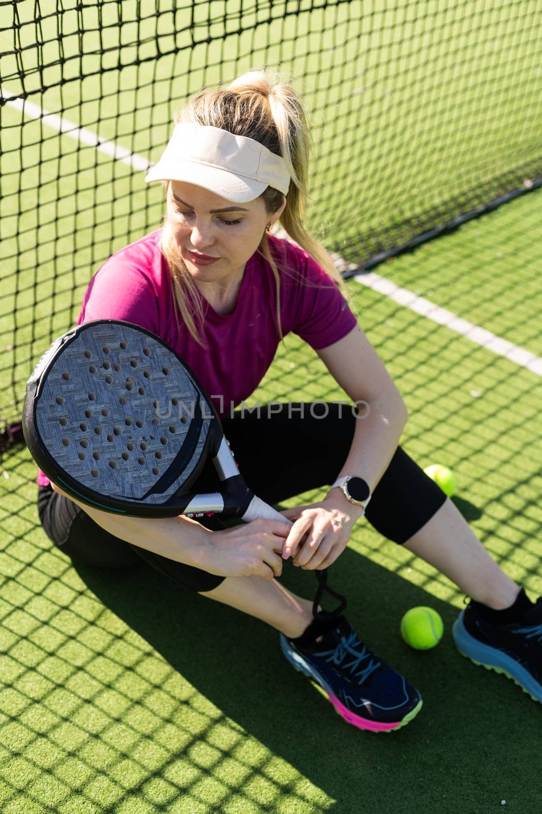 Active young woman trying to beat the ball by Padel racket while playing tennis in the court. High quality photo