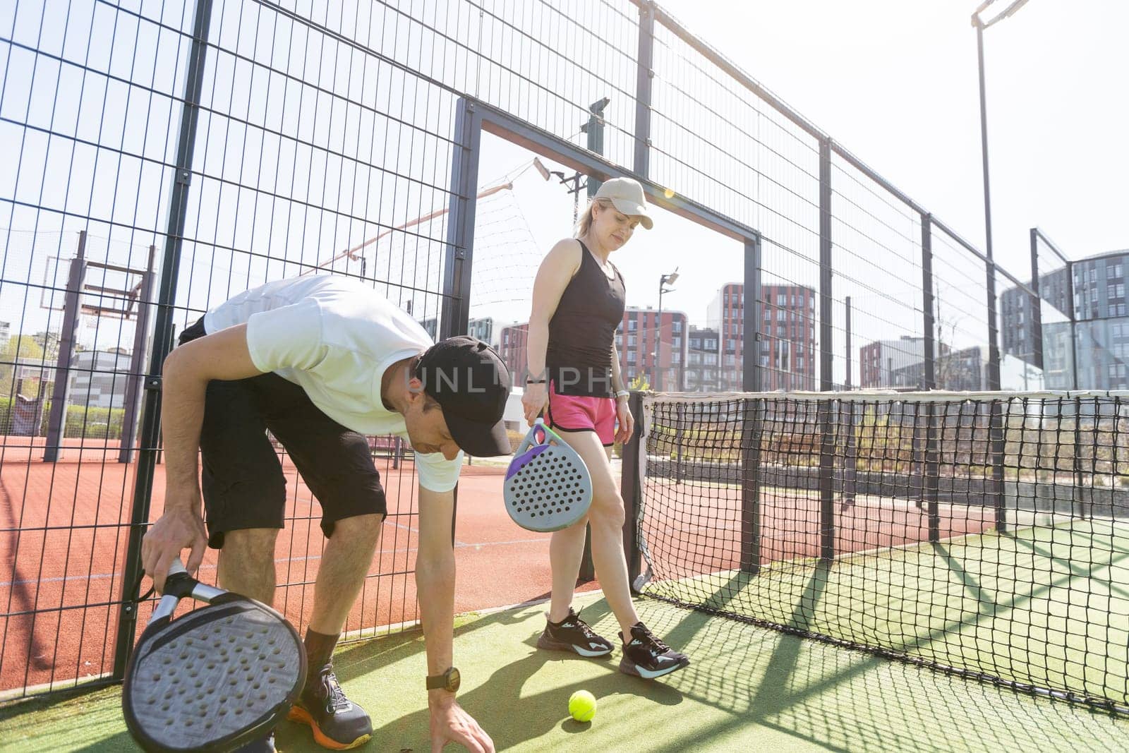 Sports couple with padel rackets posing on tennis court. High quality photo