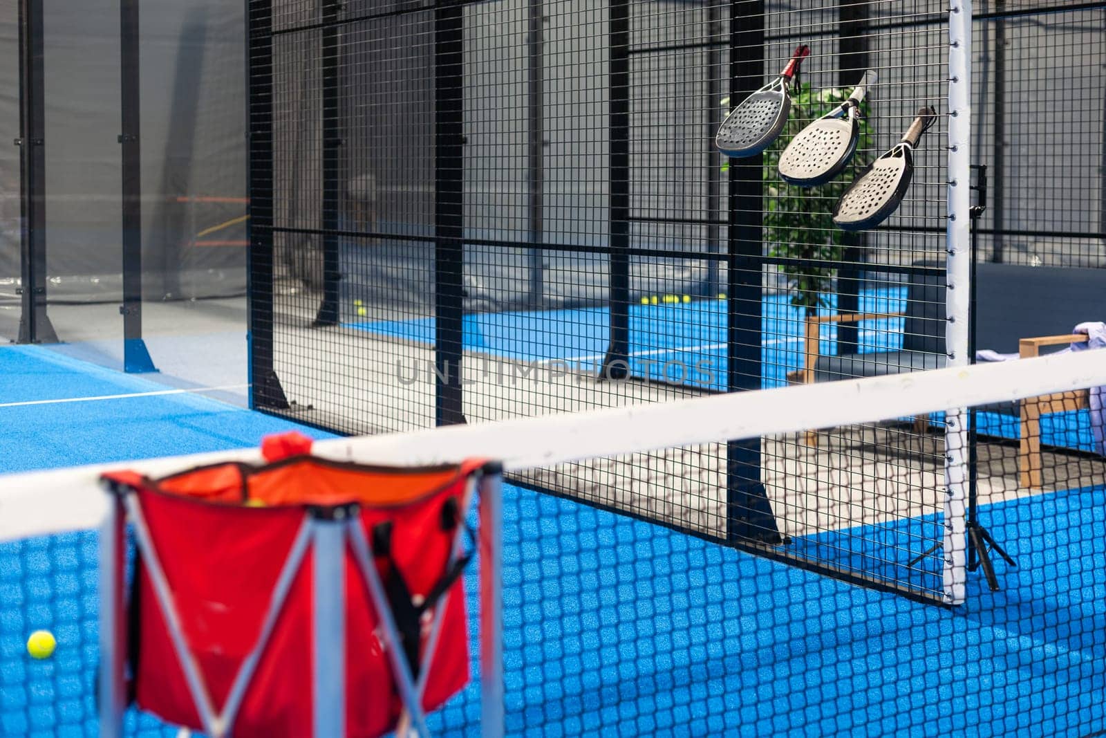 Paddle tennis rackets, balls and basket in court still life. High quality photo
