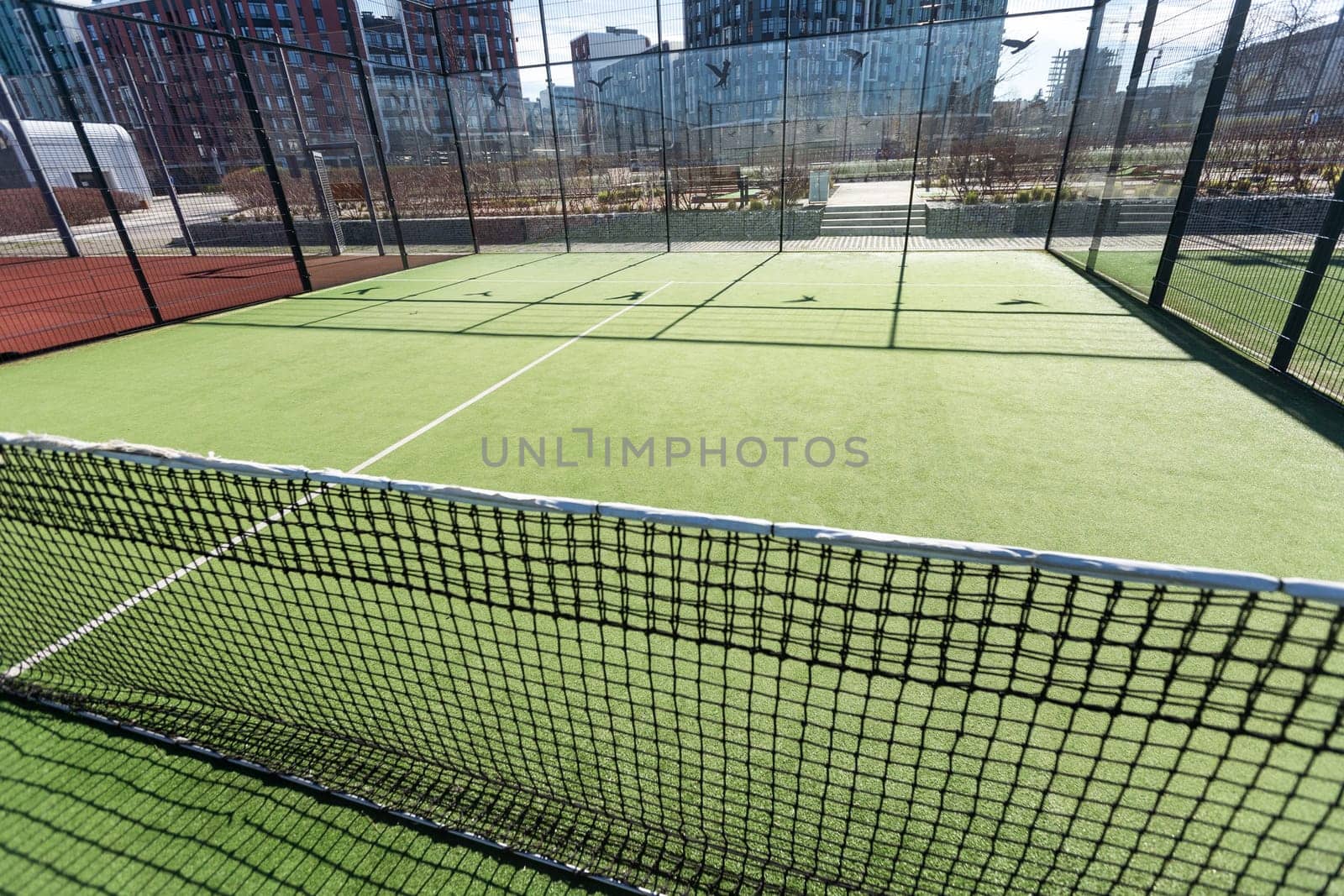 Landscaped areas of a residential development with a tennis court with high Plexiglas and metal fences. High quality photo