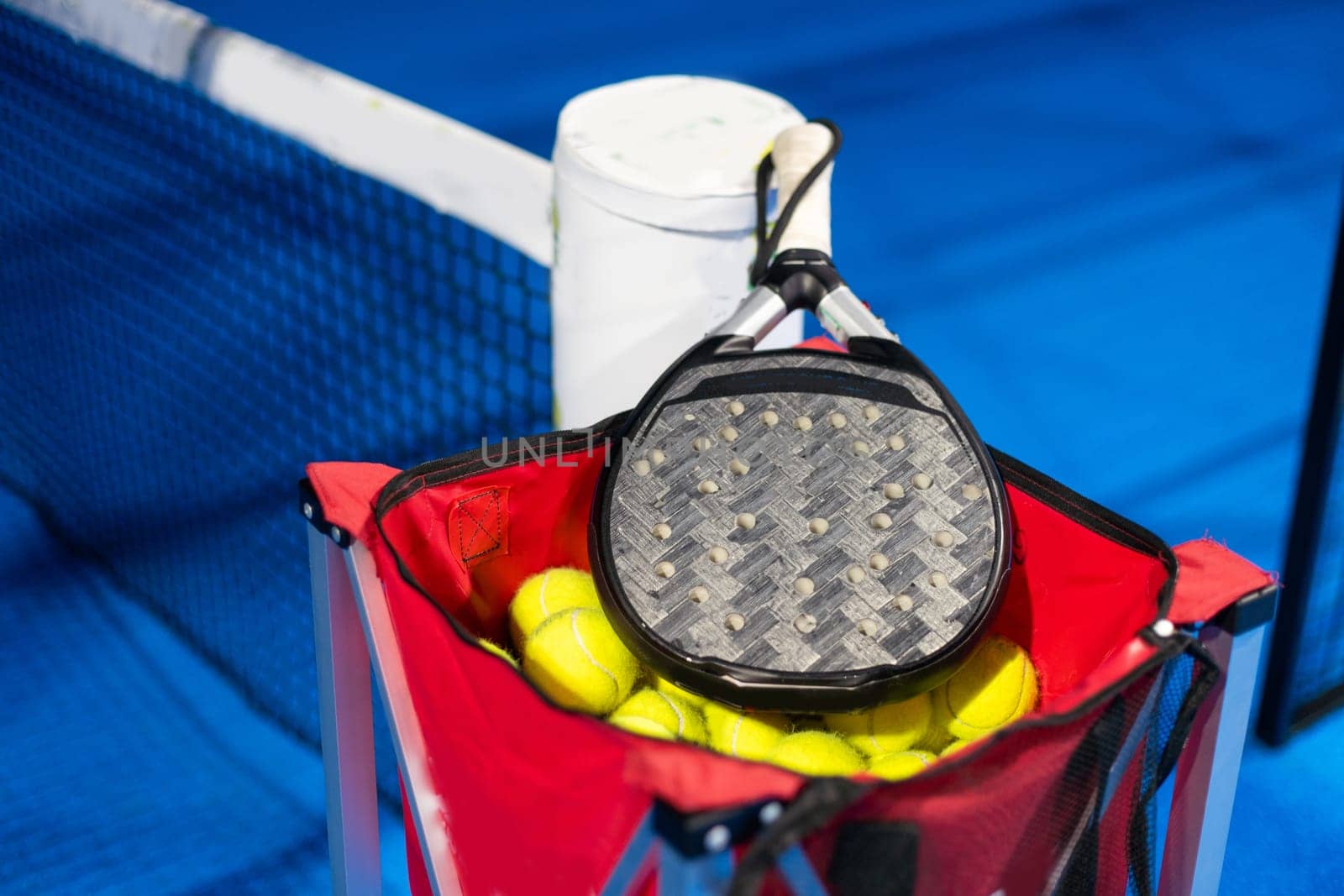 Black professional paddle tennis racket and ball with natural lighting on blue background. Horizontal sport theme poster, greeting cards, headers, website and app. High quality photo