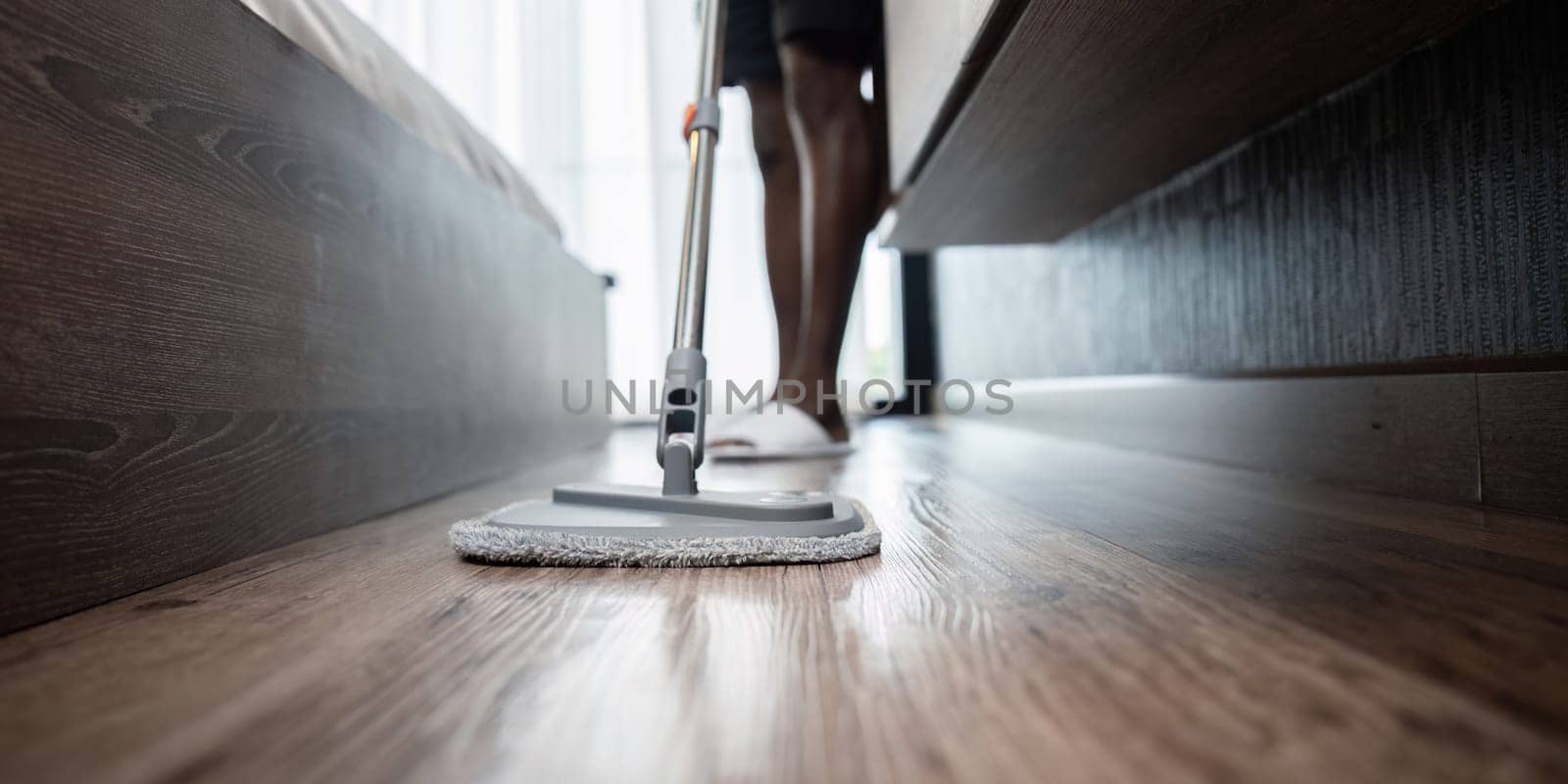 African American man young wash the floor with a mop in the room at home.