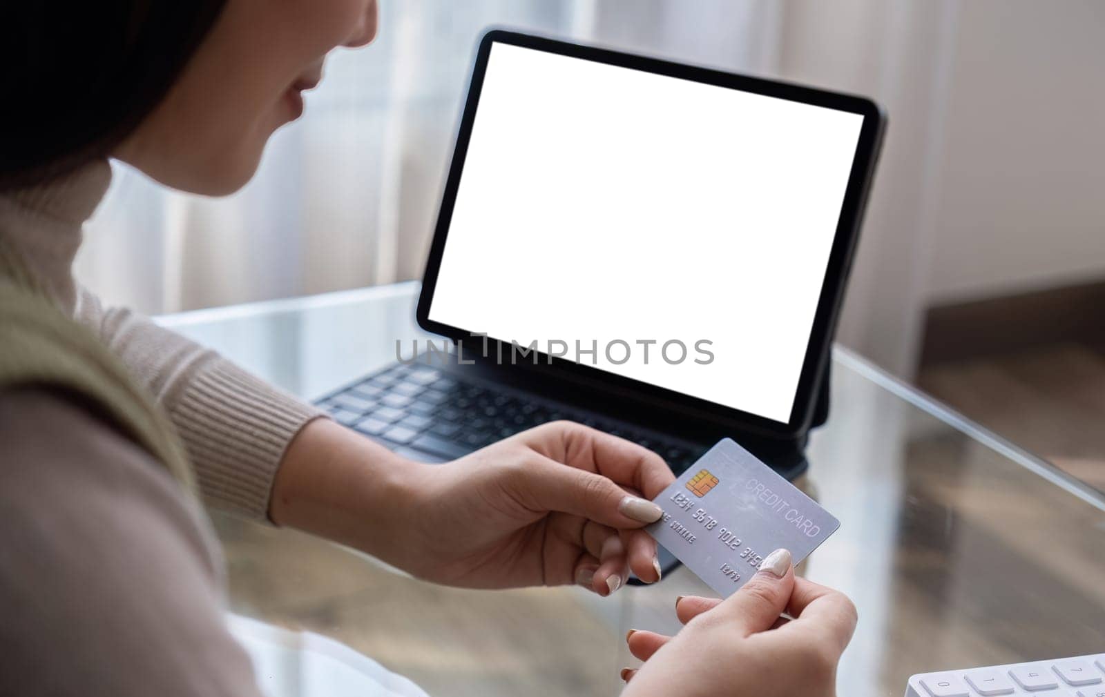 Beautiful young woman uses laptop to shop online with blank white screen Buy things from home and pay by credit card through the online banking app by phone by wichayada