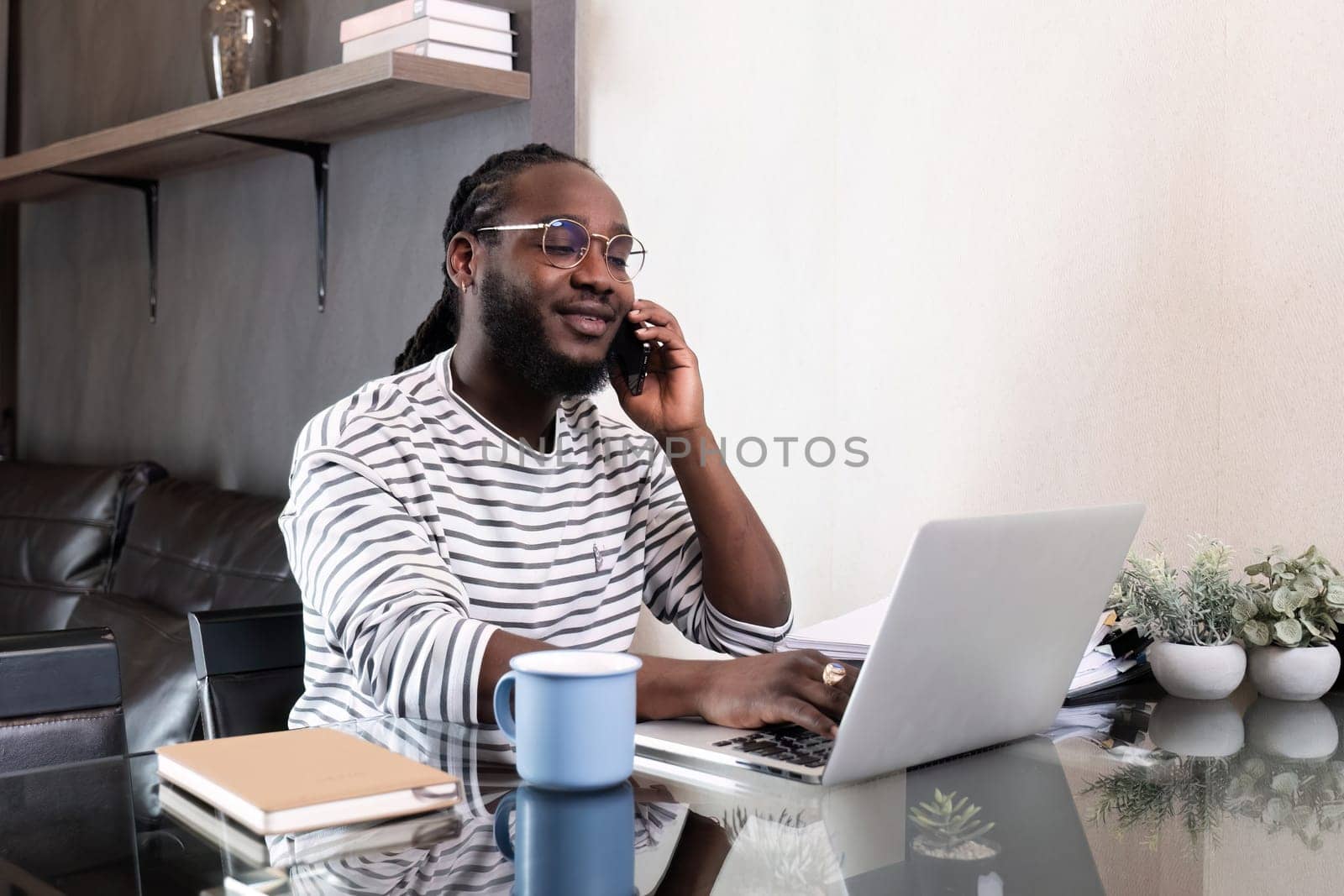 Young African American businessman spends his weekend working from home using his laptop in the living room..