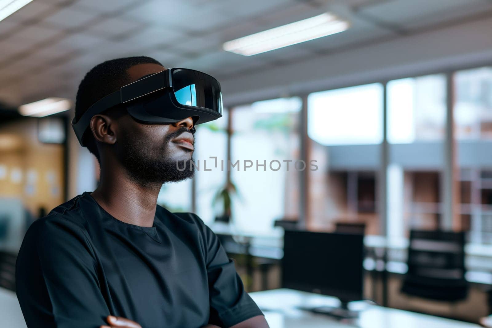 Portrait of a handsome African male businessman in a black T-shirt with virtual reality glasses standing sideways in the office with a copy of the space on the right, side view close-up.