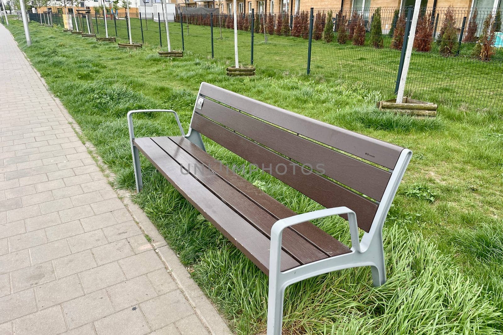 In the city, there is a bench for rest on the side of the pedestrian sidewalk. High quality photo