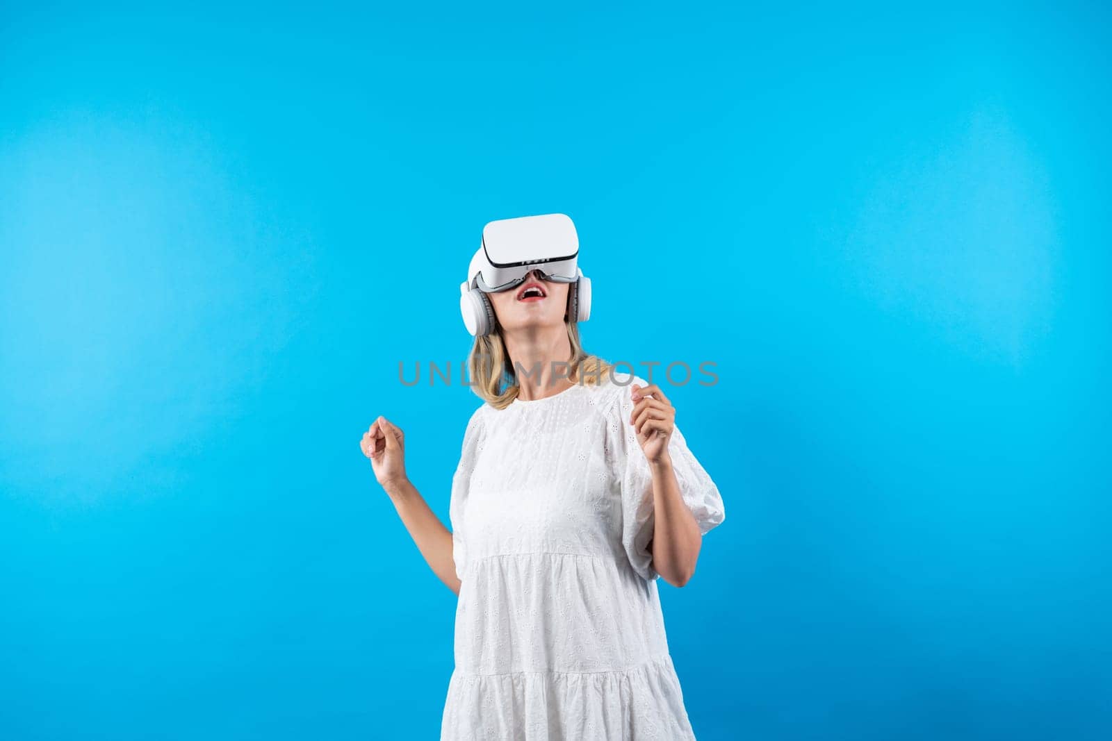 Skilled girl in pajamas excited with metaverse by using VR goggle at background. Caucasian woman surprised while looking around at futuristic view looking though visual reality goggles. Contraption.