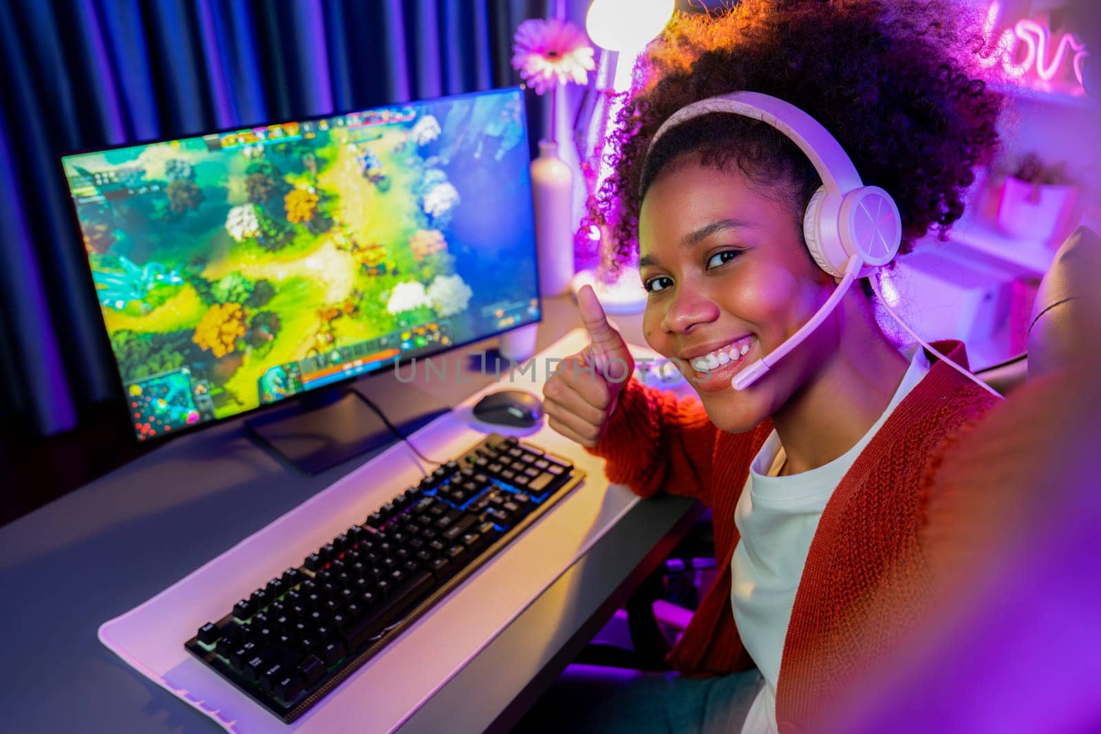 Host channel of gaming streamer, African girl playing fighting Moba game with joystick, wearing pastel headsets with mic, looking at the camera against background in neon color room. Tastemaker.