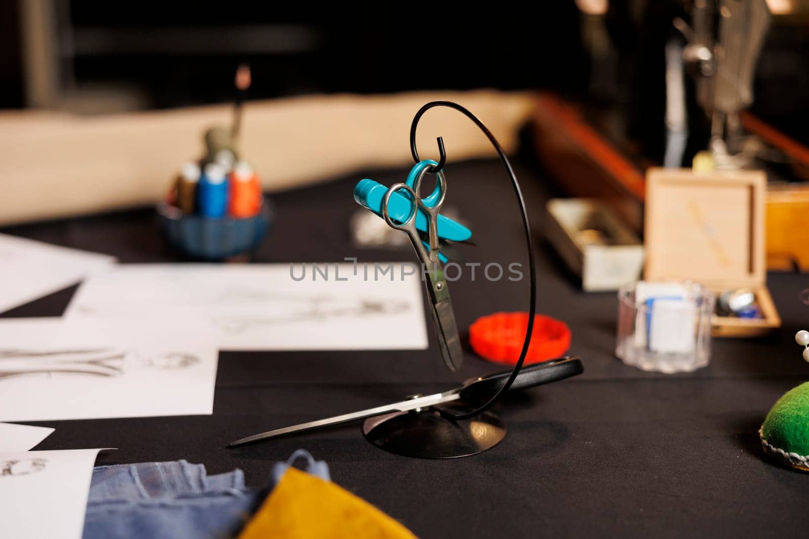 Close up focus shot on professional expert level scissors used in premium upscale tailoring studio. Blurry background of sewing instruments on table in atelier shop workplace