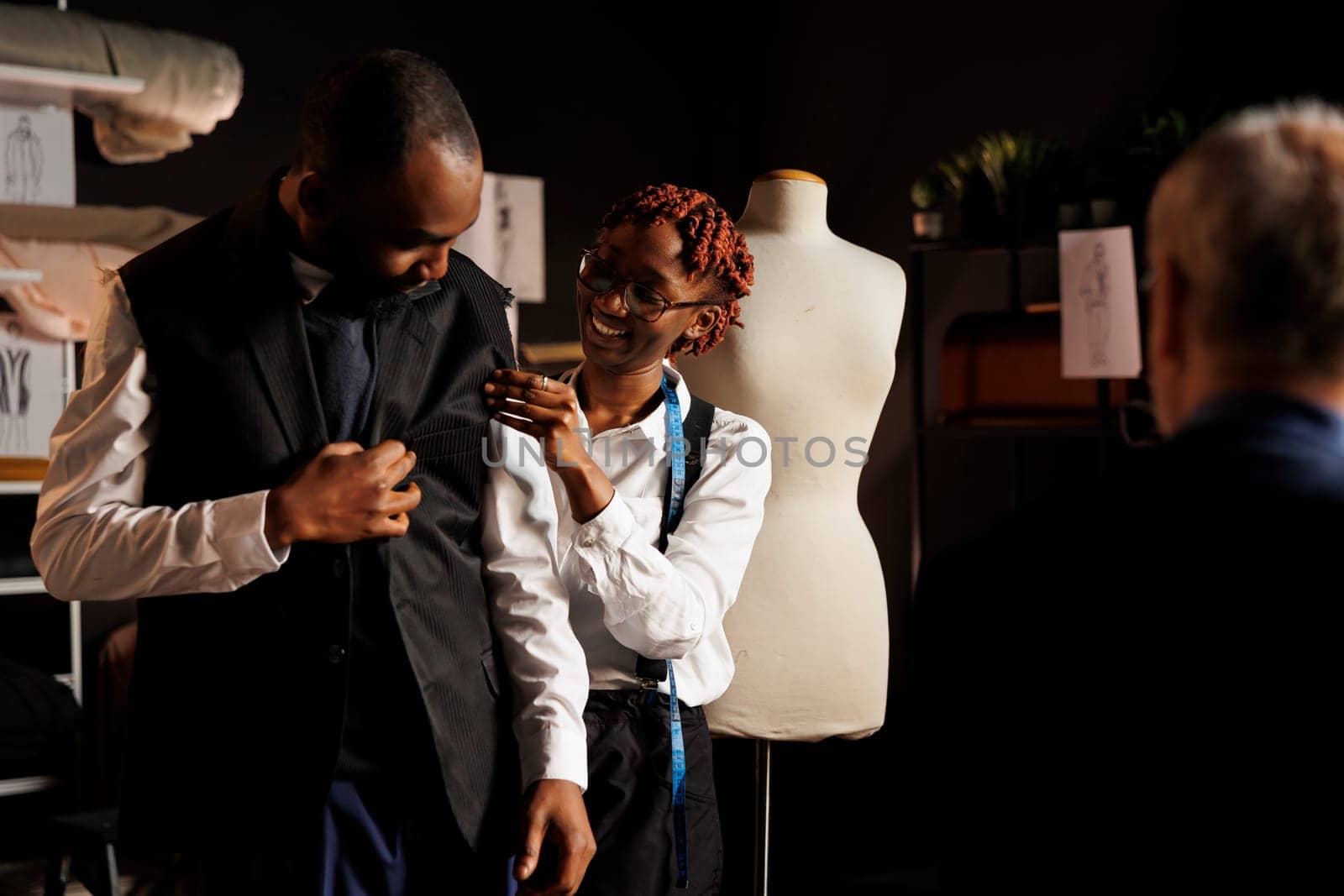 Seamstress helping client try on attire by DCStudio