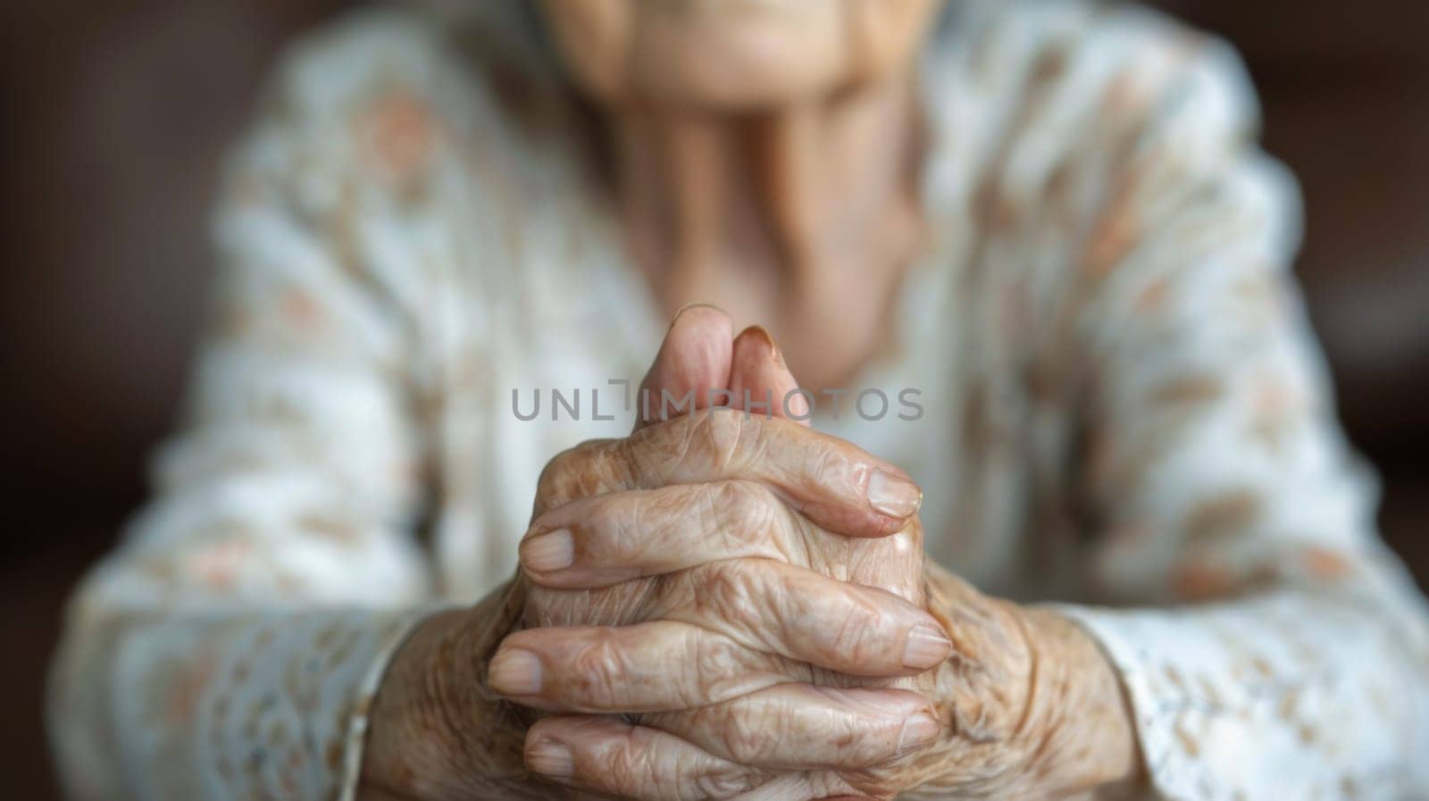 An old woman with hands folded in prayer on a table