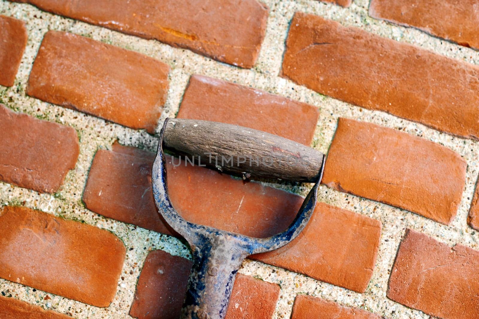 Brick, wall and cement with handle of spade for gardening, outside and block with concrete for home build. Masonry, brickwork and weather for outdoor stone architecture, weathered and aged material.