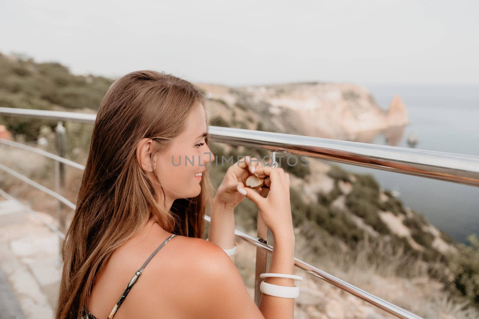 Hand, lock, heart, love, valentines day. Close up view of a woman holding a heart shaped lock that is locked onto a chain link fence.