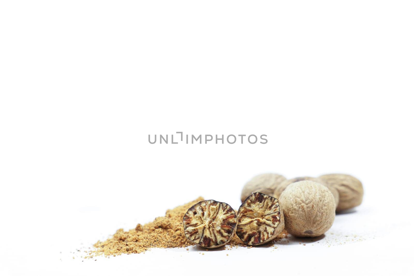 whole nutmeg, halved and ground, on a wooden spoon isolated on a white background and copy space