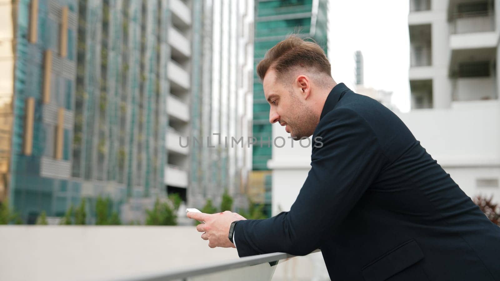 Businessman using phone to chatting with team while standing roof top. Urbane. by biancoblue