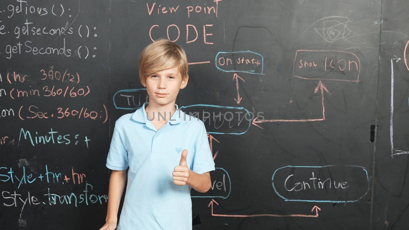 Smart caucasian boy standing at blackboard with engineering prompt or system code and showing a thumb. Student planing a project by using coding and programing system in STEM classroom. Erudition.