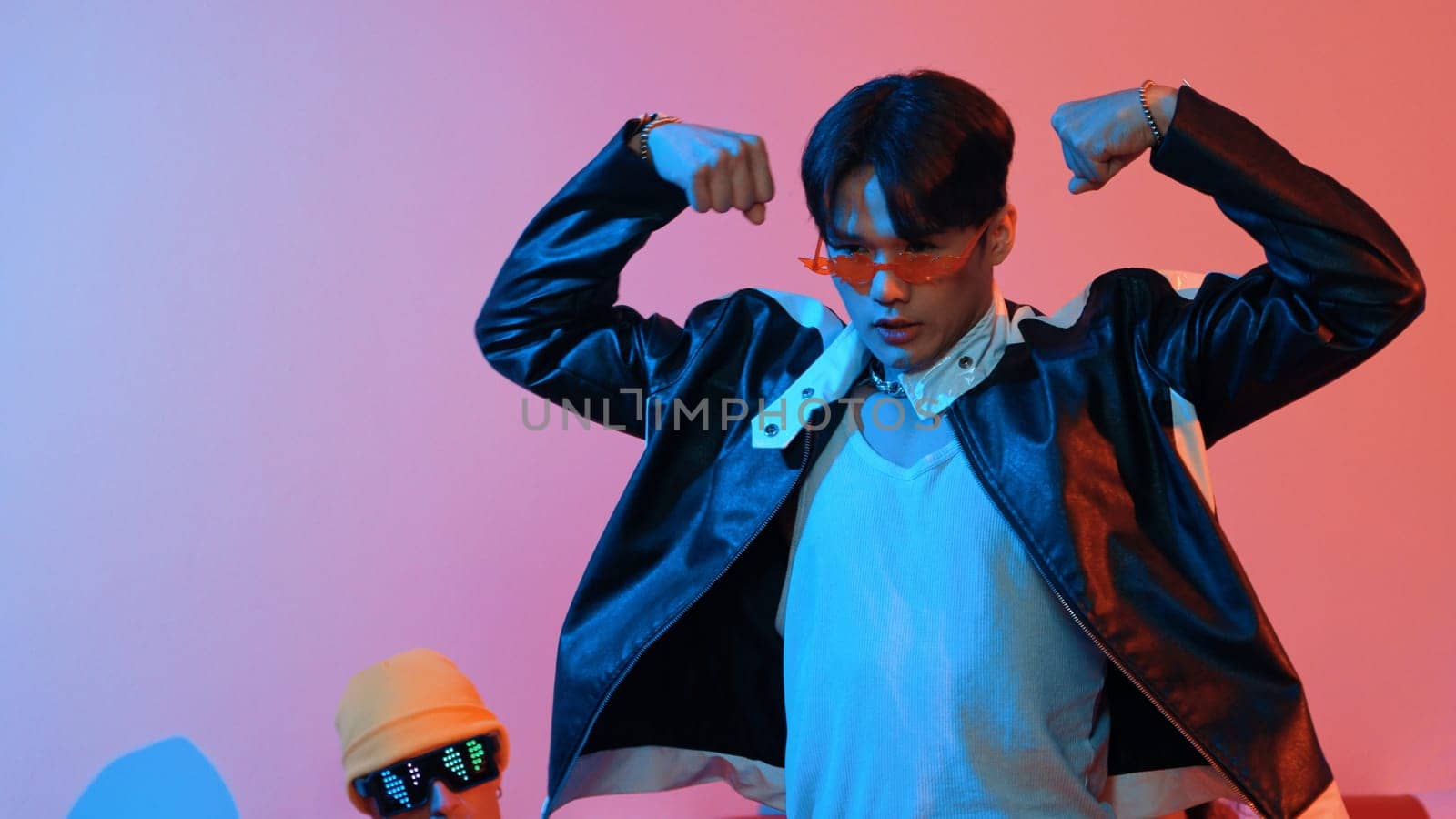 Attractive asian street dancer perform freestyle movement with neon light. Professional performer practicing moving to hip hop music with diverse friends or team at studio with led light. Regalement.