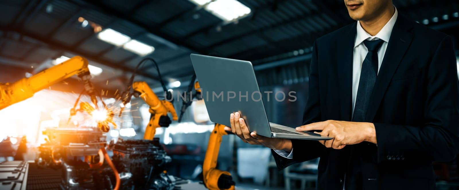 MLB Engineer use advanced robotic software to control industry robot arm in factory. Automation manufacturing process controlled by specialist using IOT software connected to internet network.