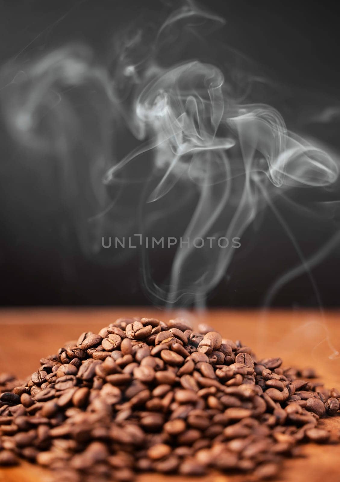 Coffee beans, smoke and table closeup in studio isolated on a black background or backdrop. Steam, caffeine and aroma of roast grain on wood desk for breakfast, organic latte and morning espresso.