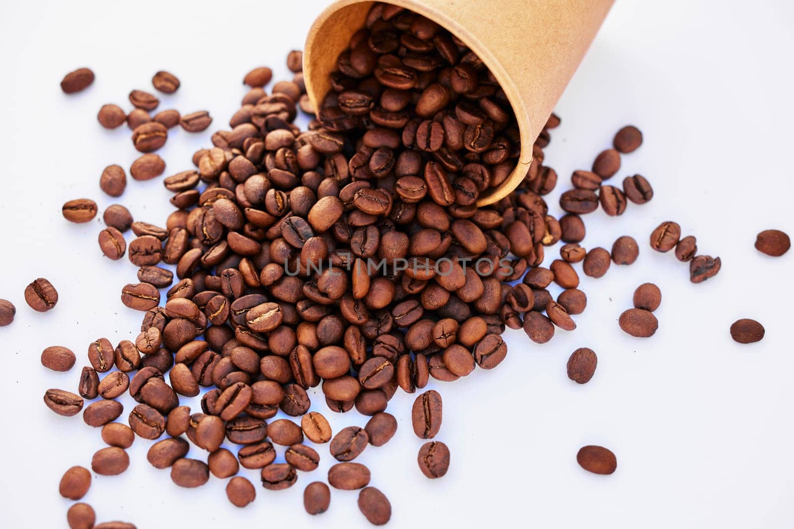 Coffee beans, top view and table closeup in studio isolated on a white background or backdrop. Above, caffeine and roast grain in cup for natural breakfast, organic latte or espresso in the morning.