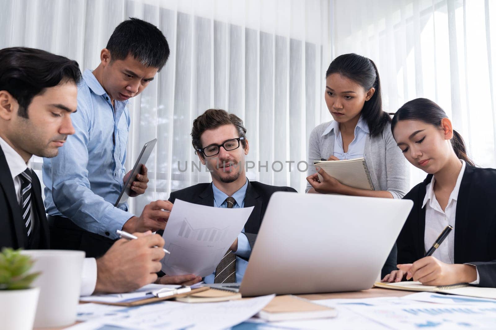 Diverse group of business analyst team analyzing financial data report paper on office table. Chart and graph dashboard by business intelligence analysis for strategic marketing planning Meticulous