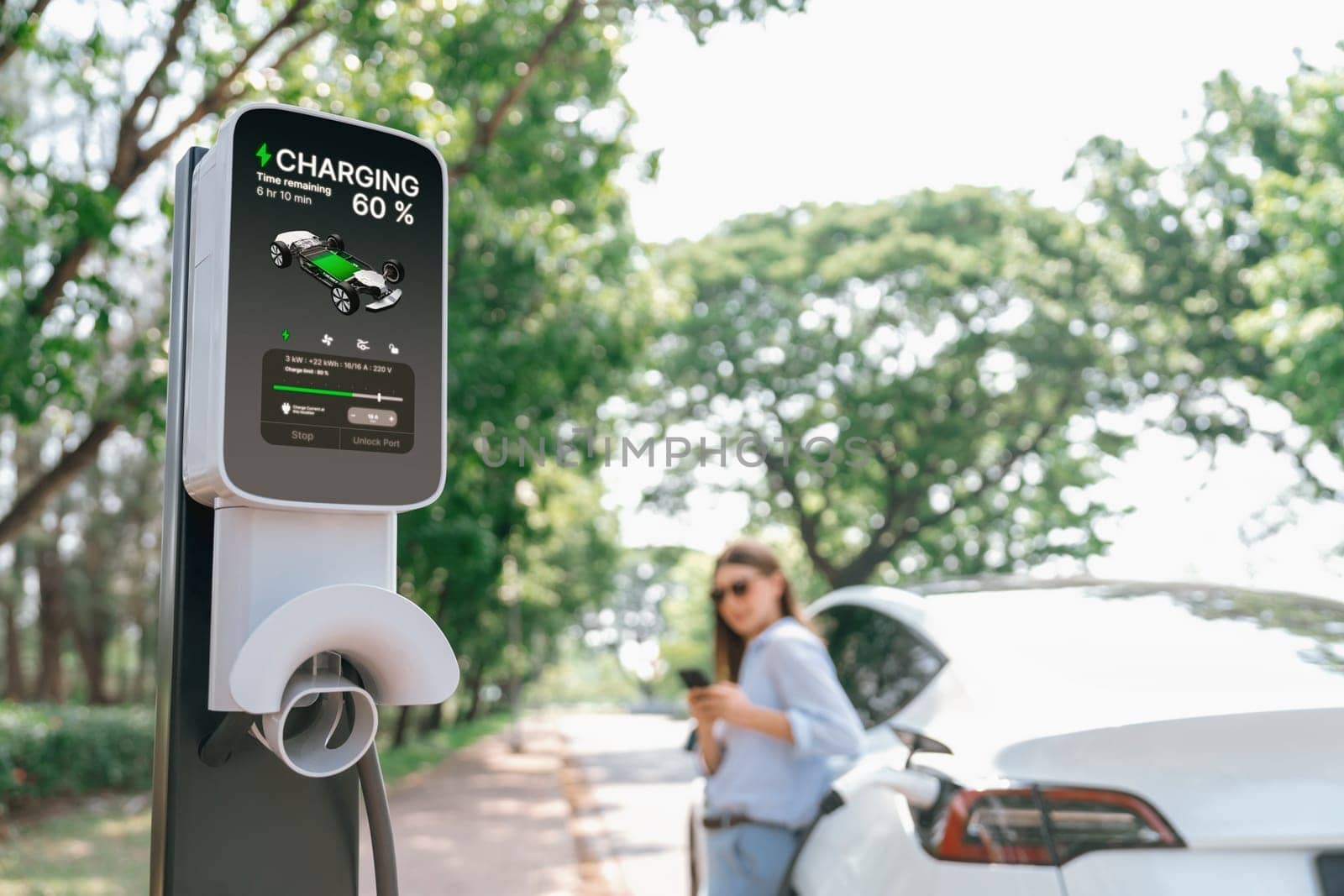 Young woman using smartphone online banking application to pay for electric car battery charging from EV charging station during vacation holiday road trip at national park or summer forest. Exalt