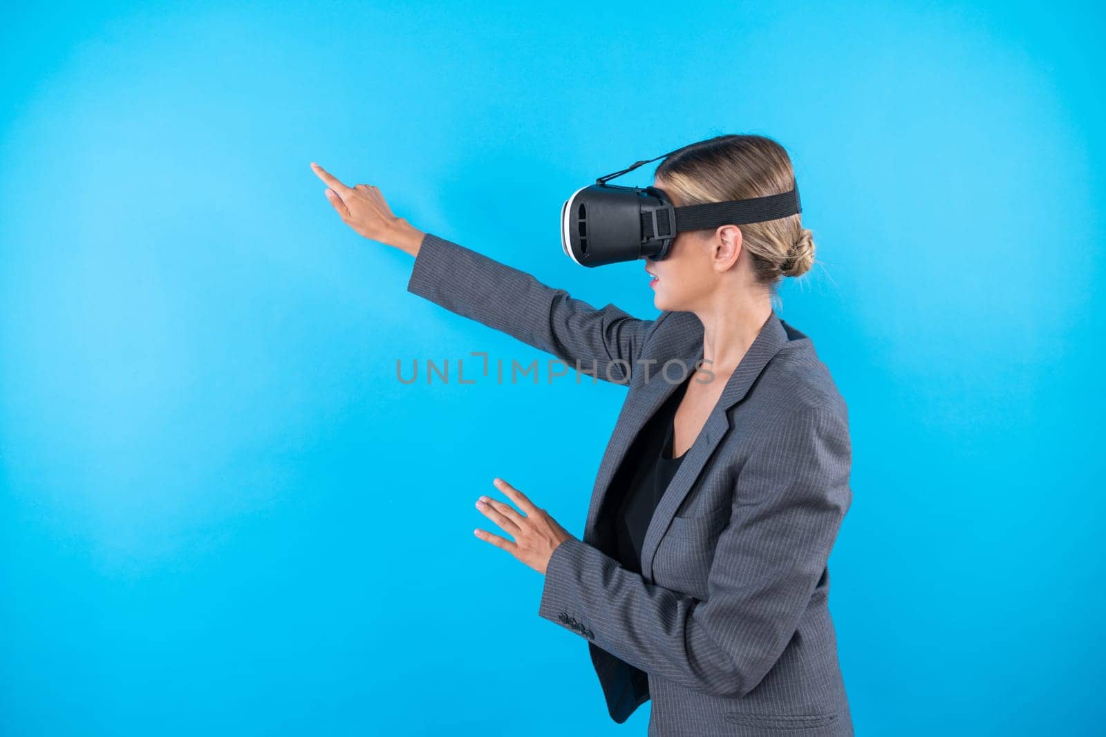 Caucasian business woman excited to explore visual reality world while standing and pointing at data. Skilled project manager wearing VR goggle and suit. Technology innovation concept. Contraption.