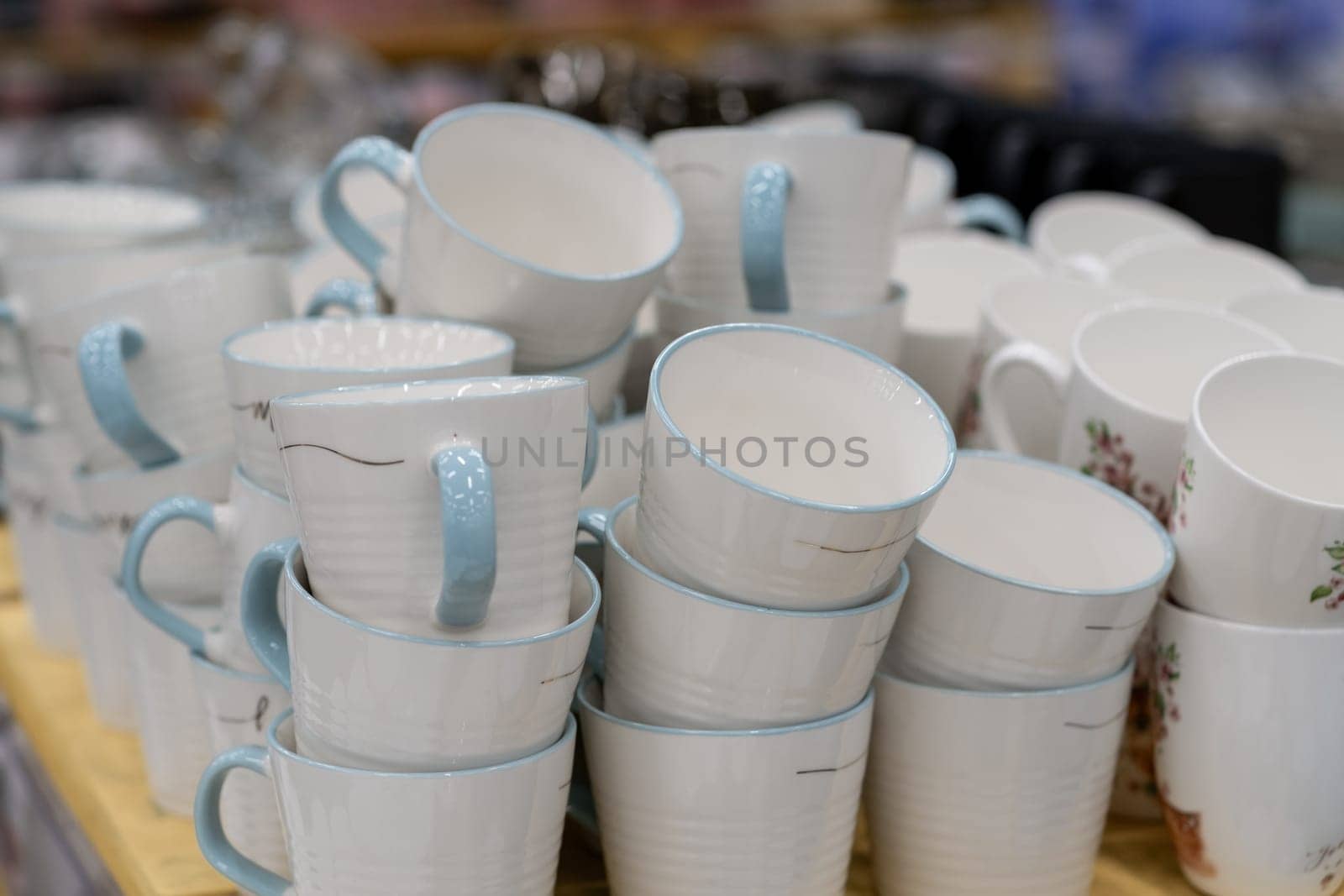 A stack of white mugs and plates in the store for sale. White and clean dishes by AnatoliiFoto
