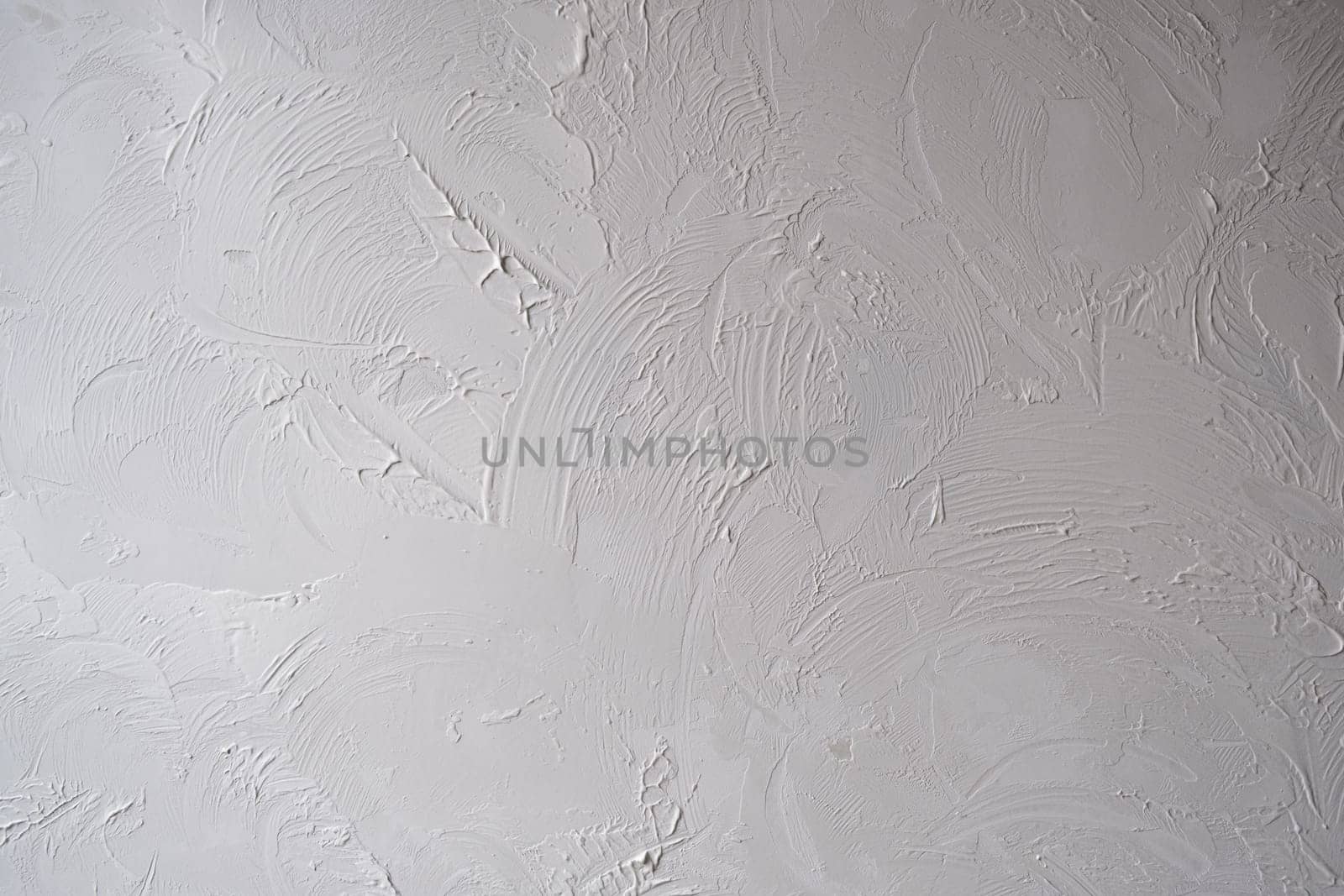 Applying decorative putty. White abstract texture of surface covered with putty. textured background of filler paste applied with putty knife in irregular dashes and strokes. Rough surface plaster
