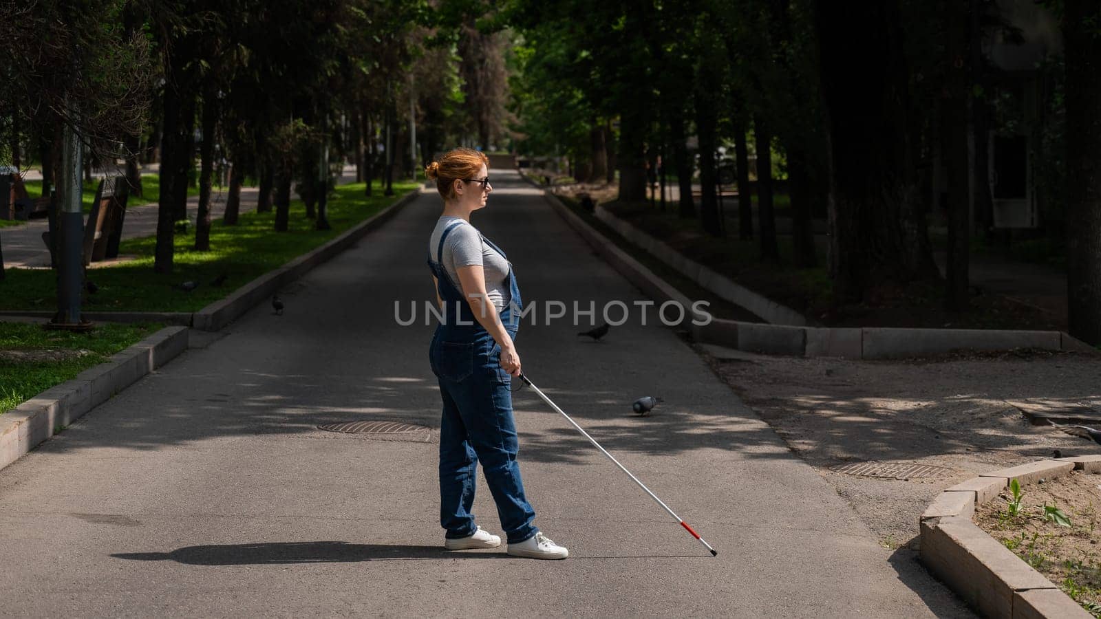 Blind pregnant woman crosses the street with the help of a tactile cane