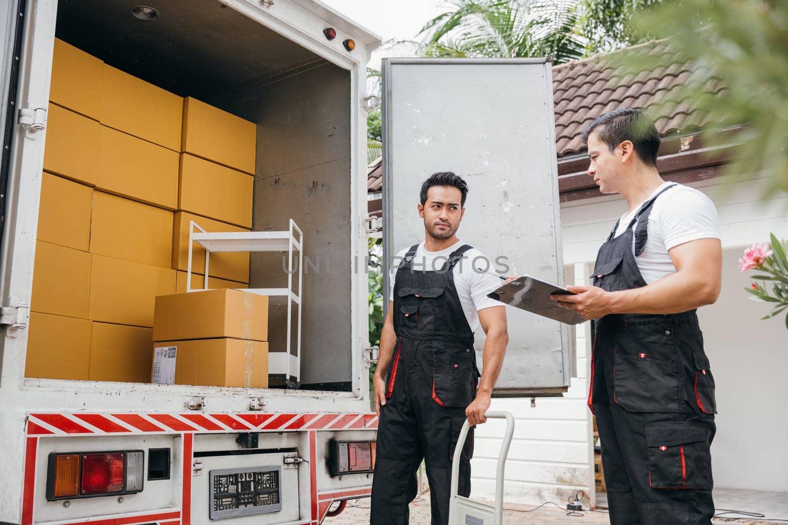 Employee teamwork shines as they unload boxes from the truck for customers moving house. The company efficient service guarantees happiness in their new home. Moving Day