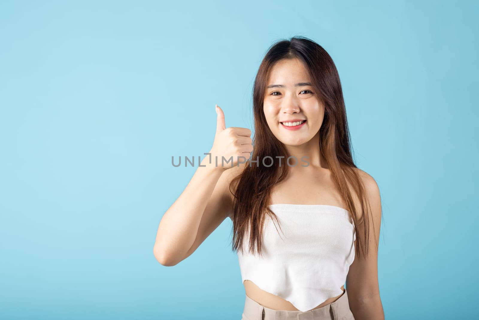 Beauty skin care and cosmetics concept. Asian young woman showing thumb up in approval studio shot isolated on blue background, like and good, Happy female show finger thumbup