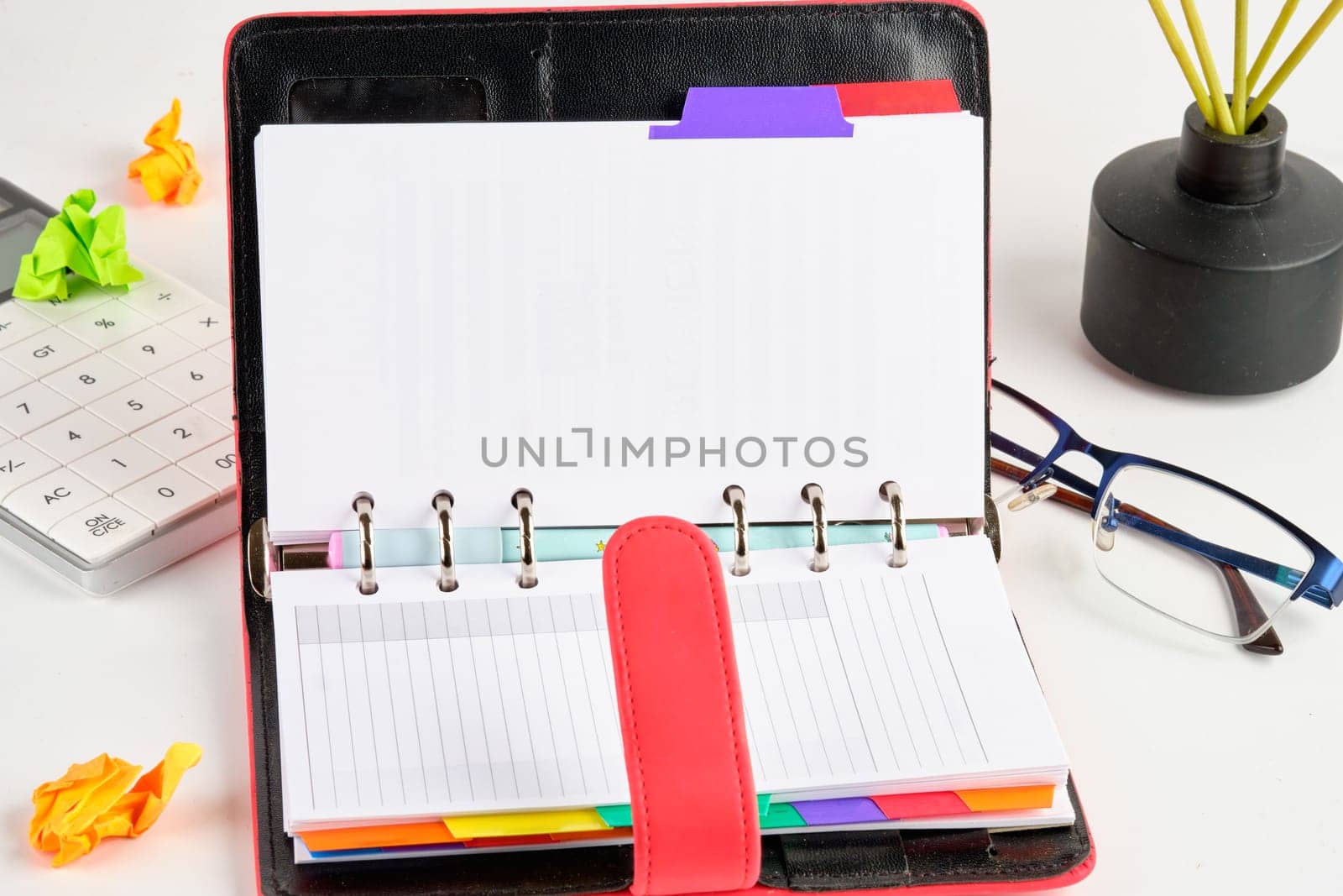 An open notebook with a place to copy on a white background next to a calculator, glasses