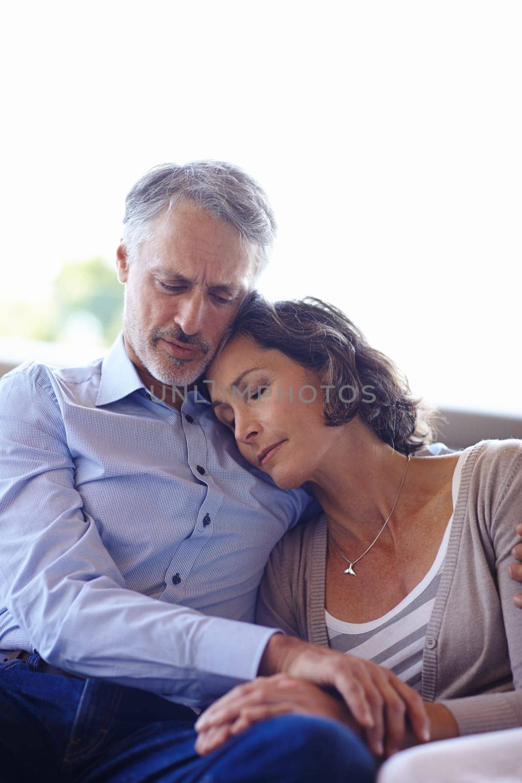 Mature couple, hug and relax on couch for love, commitment and affection in marriage. People, home and comfortable in embrace on sofa and care in relationship, romance and bonding together in lounge by YuriArcurs