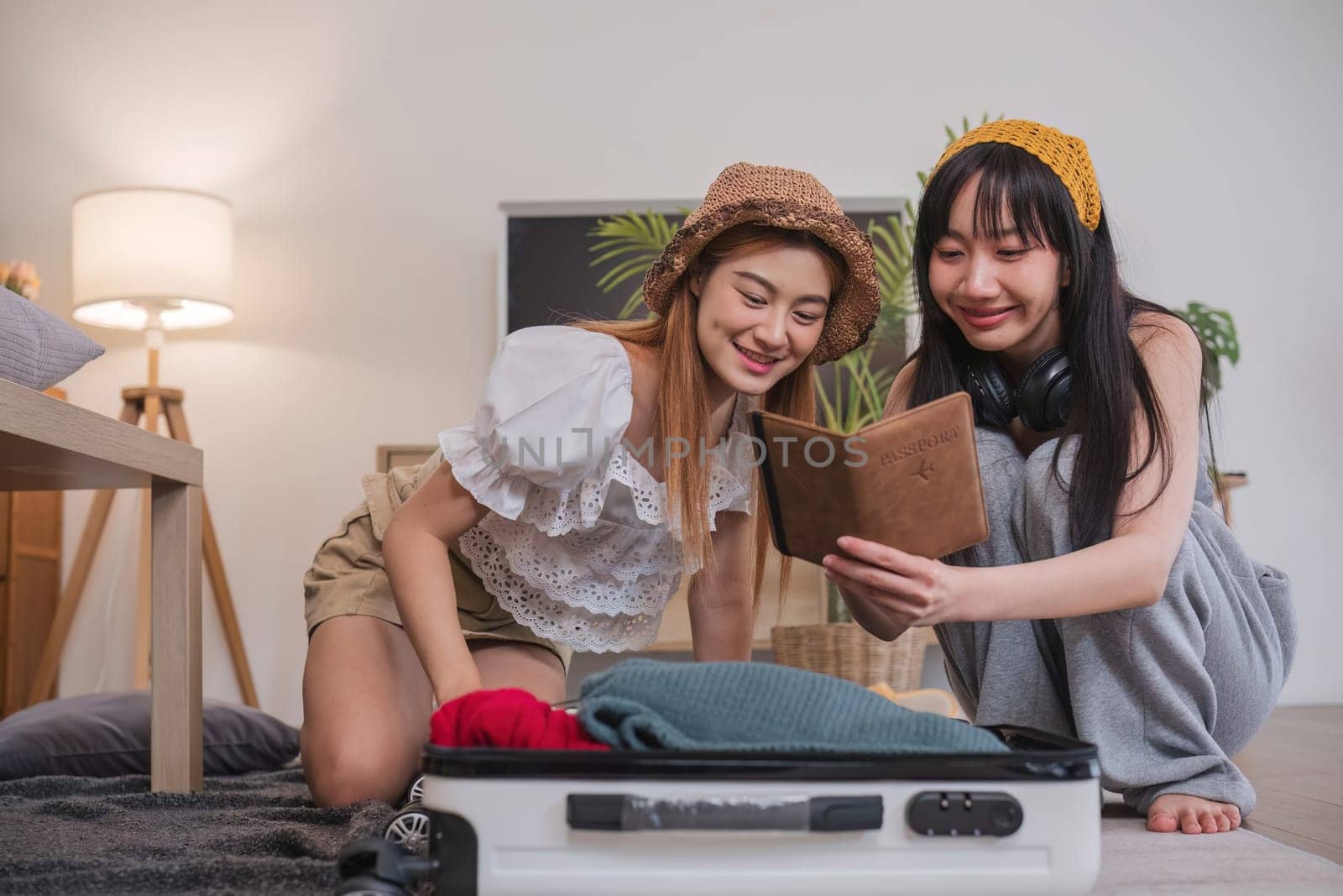 Two women checking passports while sitting on the floor next to suitcases.